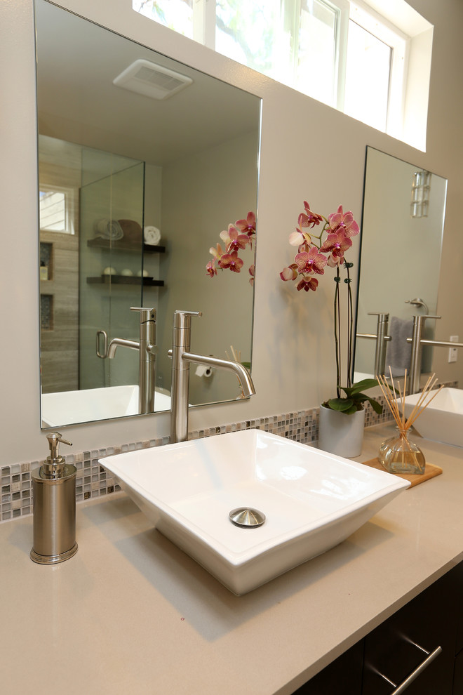 This is an example of a mid-sized modern master bathroom in Los Angeles with flat-panel cabinets, dark wood cabinets, a curbless shower, a two-piece toilet, multi-coloured tile, limestone, beige walls, porcelain floors, a vessel sink and engineered quartz benchtops.