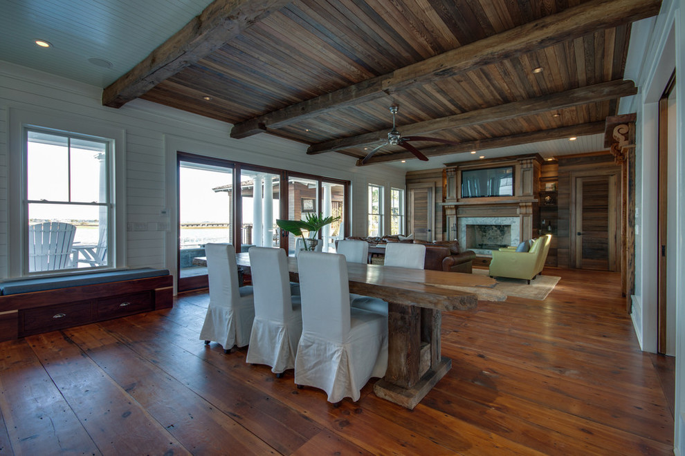 This is an example of a beach style dining room in Charleston with medium hardwood floors, a standard fireplace and a stone fireplace surround.