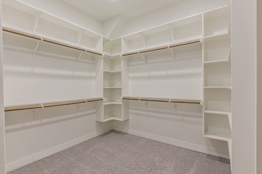 This is an example of a large arts and crafts gender-neutral walk-in wardrobe in Austin with open cabinets, white cabinets, carpet and grey floor.
