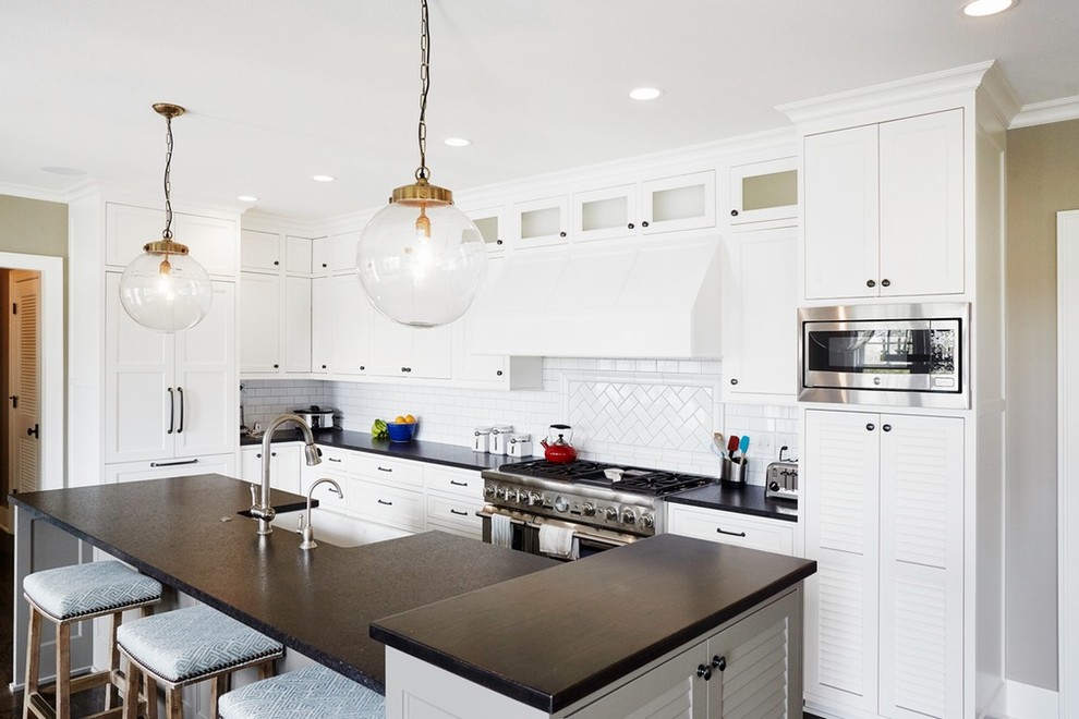 Inspiration for a mid-sized transitional l-shaped dark wood floor and brown floor eat-in kitchen remodel in Minneapolis with a farmhouse sink, shaker cabinets, white cabinets, solid surface countertops, white backsplash, subway tile backsplash, stainless steel appliances and an island