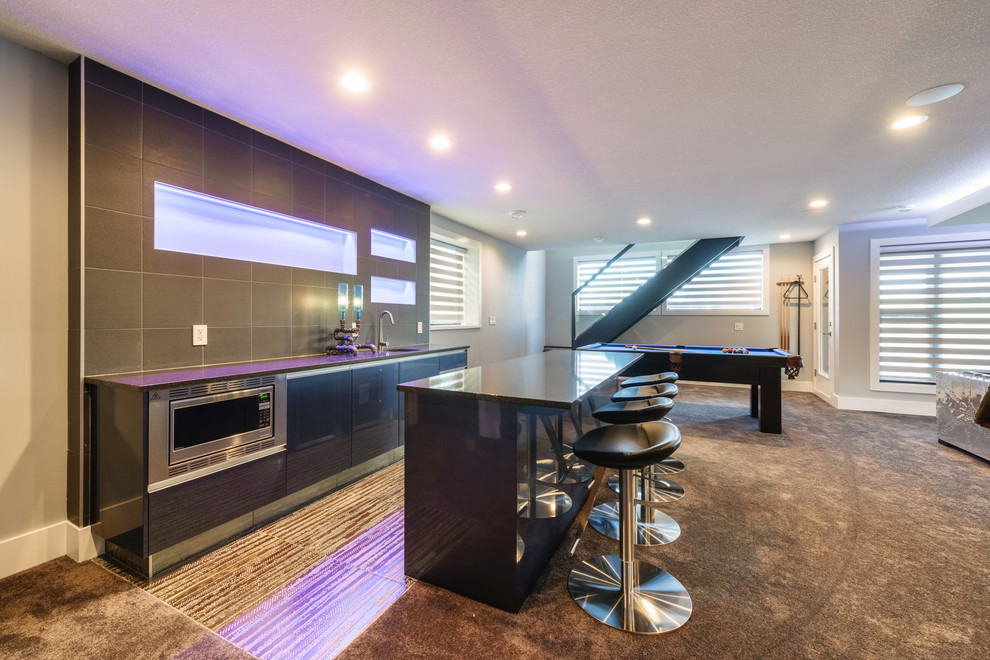 Photo of a mid-sized modern single-wall seated home bar in Edmonton with an undermount sink, flat-panel cabinets, black cabinets, granite benchtops, brown splashback, porcelain splashback, carpet and brown floor.
