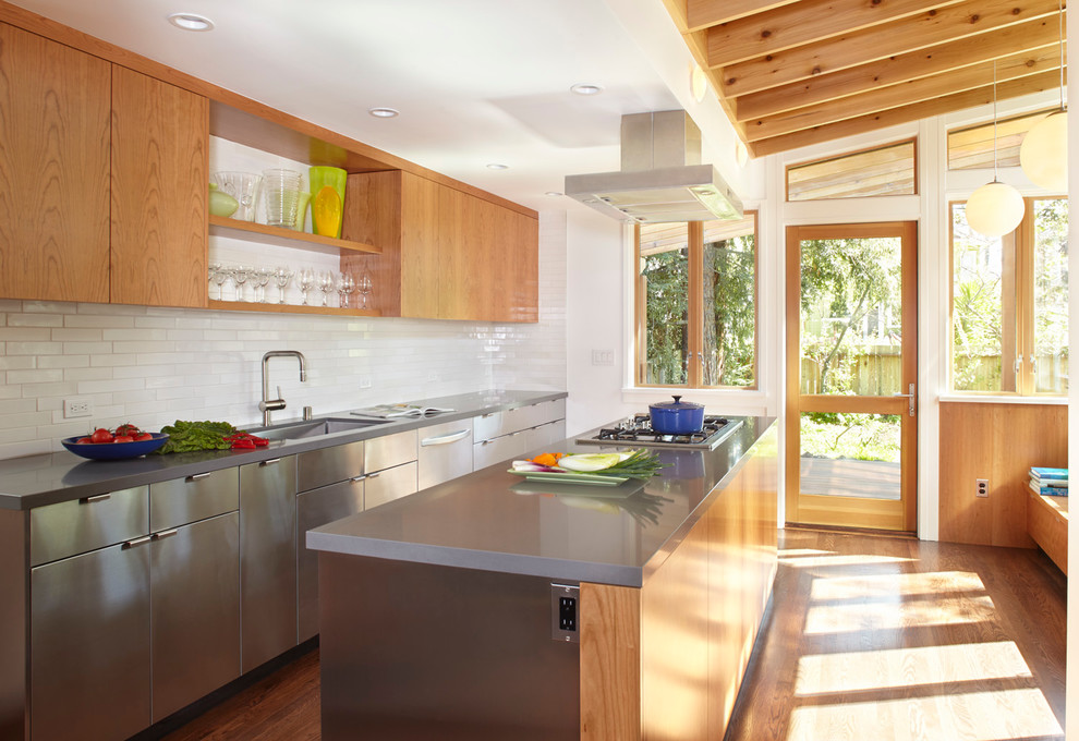 Design ideas for a contemporary galley kitchen in San Francisco with an undermount sink, flat-panel cabinets, stainless steel cabinets, white splashback, stainless steel appliances, medium hardwood floors, with island and quartz benchtops.