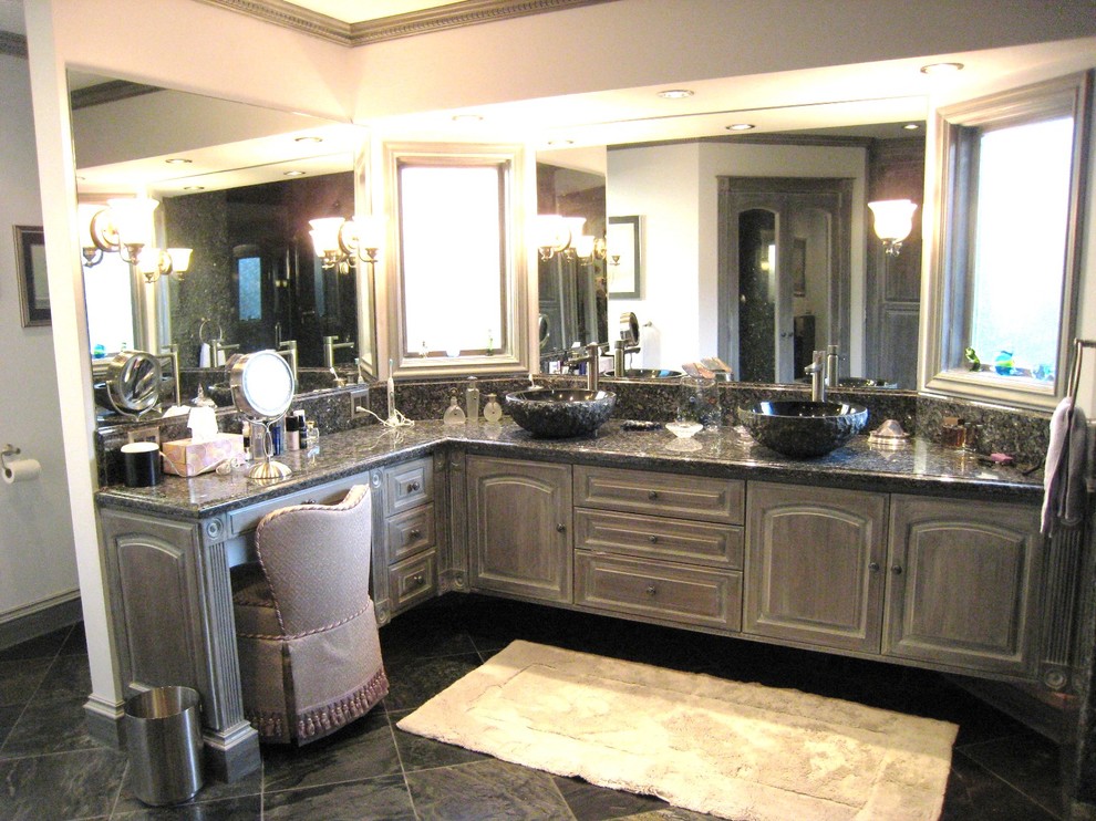 Photo of a large traditional master bathroom in Sacramento with a vessel sink, raised-panel cabinets, distressed cabinets, granite benchtops, a double shower, a one-piece toilet, gray tile, stone slab, white walls and slate floors.
