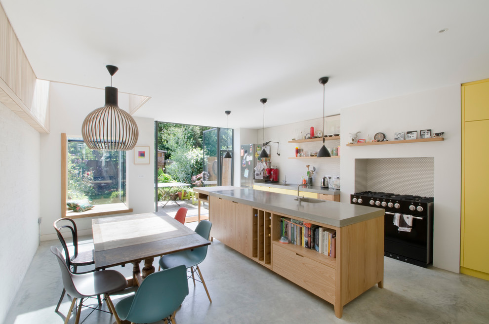 Inspiration for a contemporary galley eat-in kitchen in London with concrete floors, open cabinets, yellow cabinets, black appliances and with island.