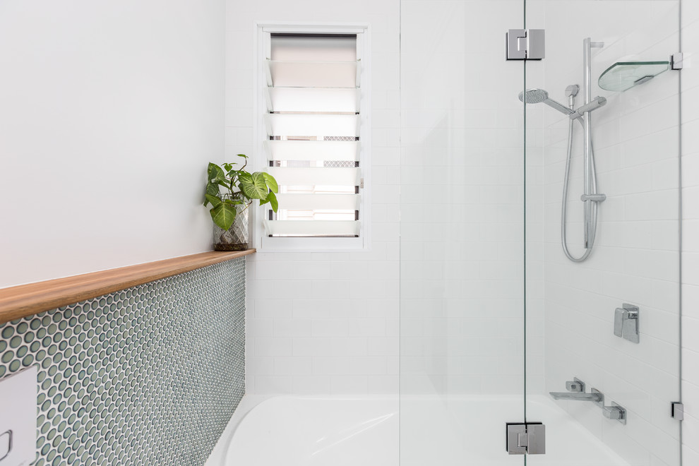This is an example of a small transitional 3/4 bathroom in Brisbane with flat-panel cabinets, blue cabinets, a drop-in tub, a one-piece toilet, blue tile, pebble tile, blue walls, cement tiles, a wall-mount sink, engineered quartz benchtops, white floor and white benchtops.