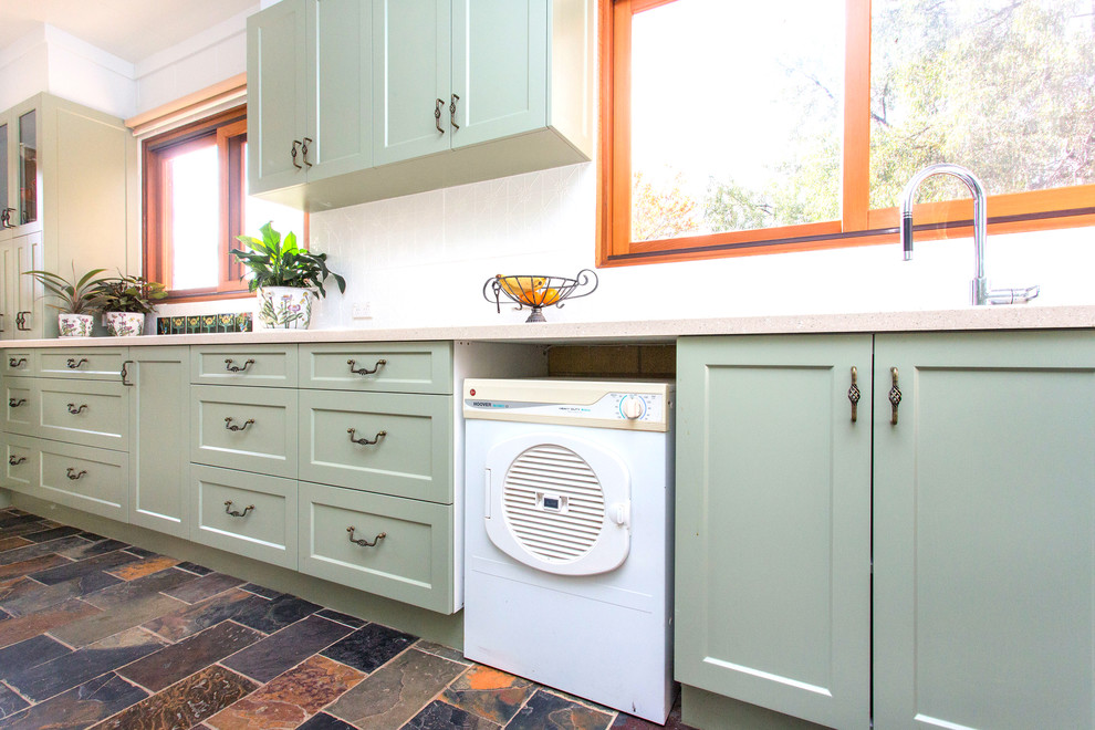 This is an example of a small country galley kitchen in Other with a double-bowl sink, shaker cabinets, green cabinets, solid surface benchtops, white splashback, metal splashback, slate floors, multi-coloured floor and beige benchtop.