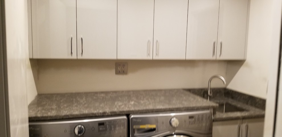 This is an example of a small modern galley dedicated laundry room in Detroit with an undermount sink, flat-panel cabinets, grey cabinets, quartz benchtops, grey walls, limestone floors, a side-by-side washer and dryer, brown floor and brown benchtop.