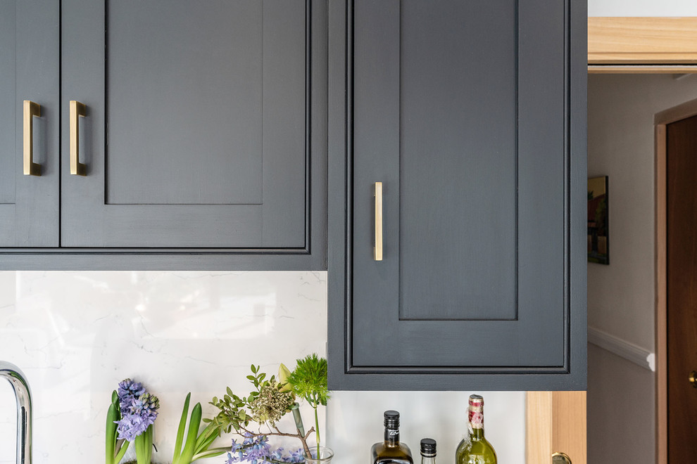 Inspiration for a small contemporary u-shaped kitchen in London with a farmhouse sink, recessed-panel cabinets, blue cabinets, quartzite benchtops, white splashback, with island and white benchtop.