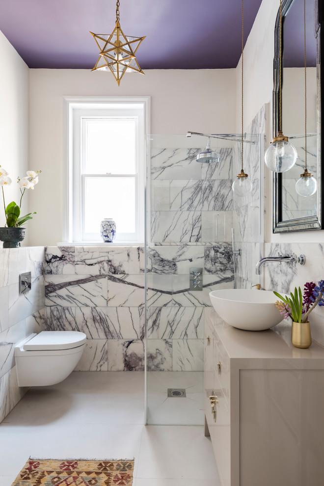 Inspiration for a mid-sized transitional 3/4 wet room bathroom in London with grey cabinets, a wall-mount toilet, white tile, stone tile, white walls, porcelain floors, a vessel sink, wood benchtops and flat-panel cabinets.
