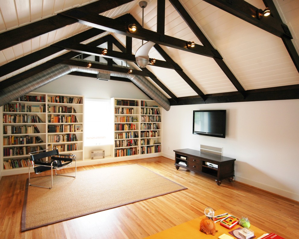 This is an example of a contemporary family room in Birmingham with a library, medium hardwood floors and a wall-mounted tv.