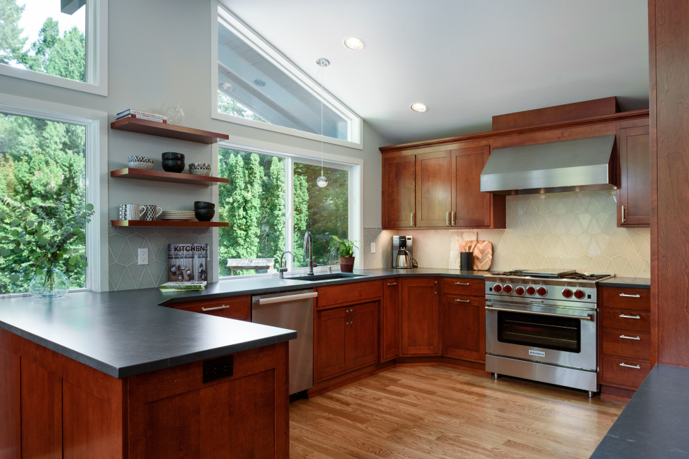 Inspiration for a large transitional u-shaped eat-in kitchen in Seattle with an undermount sink, a peninsula, recessed-panel cabinets, quartz benchtops, grey splashback, stainless steel appliances, light hardwood floors, yellow floor, black benchtop and dark wood cabinets.