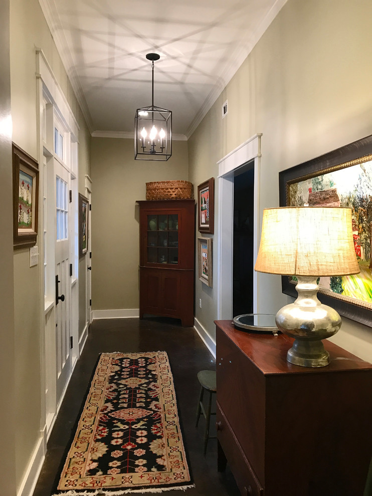 This is an example of a mid-sized arts and crafts hallway in New Orleans with beige walls and concrete floors.