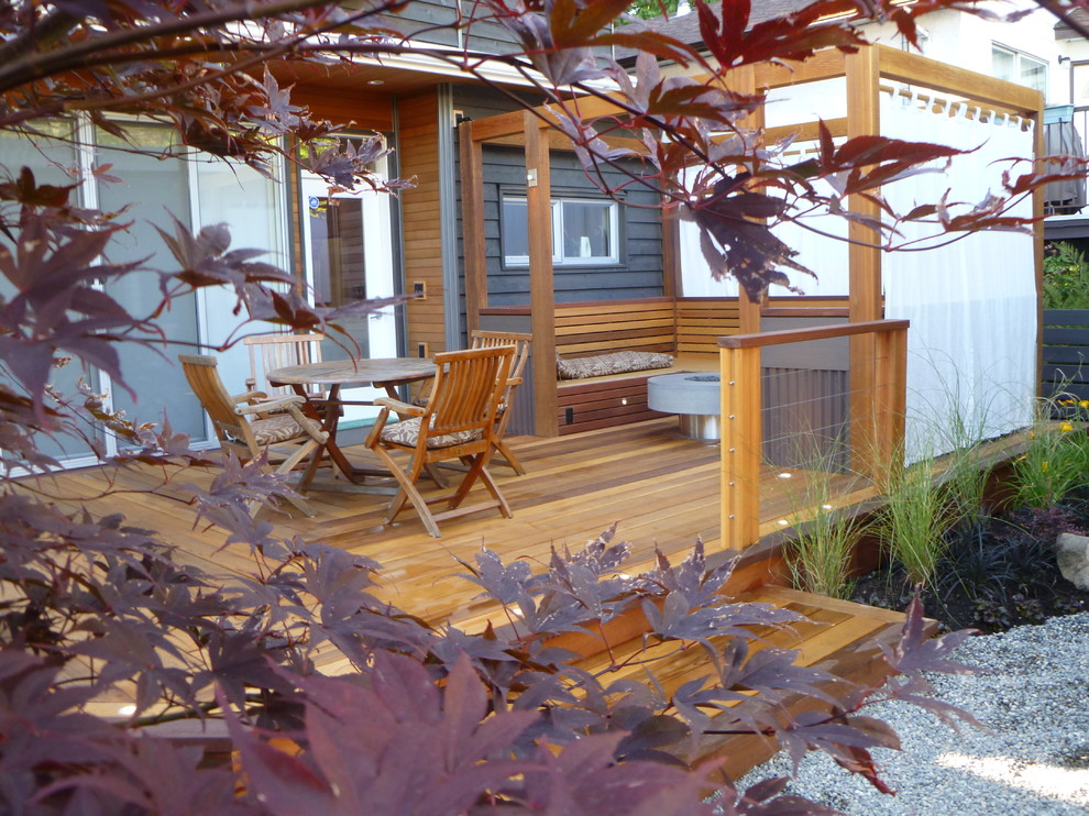 Example of a mid-sized transitional backyard deck design in Vancouver with a fire pit and a pergola