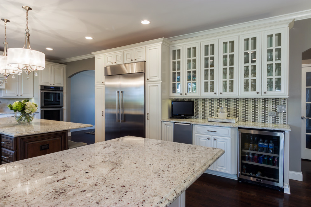 Example of a large transitional u-shaped dark wood floor kitchen design in Chicago with a double-bowl sink, raised-panel cabinets, white cabinets, granite countertops, gray backsplash, subway tile backsplash, stainless steel appliances and an island