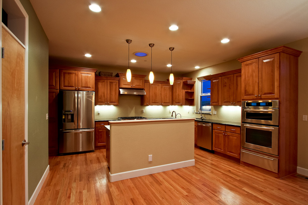 Example of a transitional l-shaped eat-in kitchen design in Denver with an undermount sink, raised-panel cabinets, medium tone wood cabinets, granite countertops and stainless steel appliances