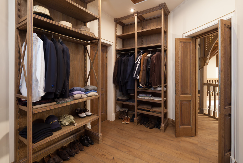 Inspiration for a large traditional gender-neutral walk-in wardrobe in Moscow with recessed-panel cabinets, distressed cabinets and dark hardwood floors.