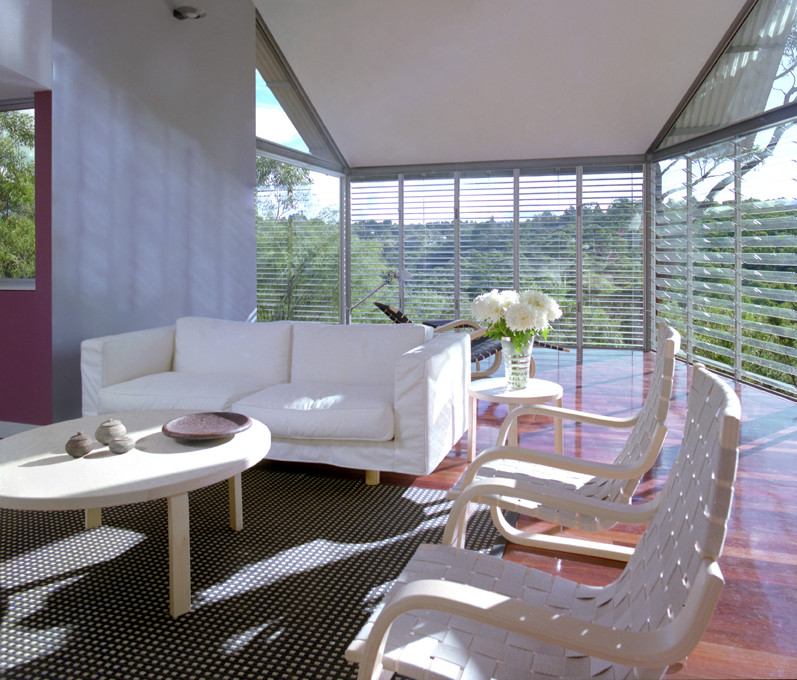 Design ideas for a mid-sized contemporary open concept living room in Sydney with a library, multi-coloured walls, medium hardwood floors, a wood stove, a concrete fireplace surround and brown floor.