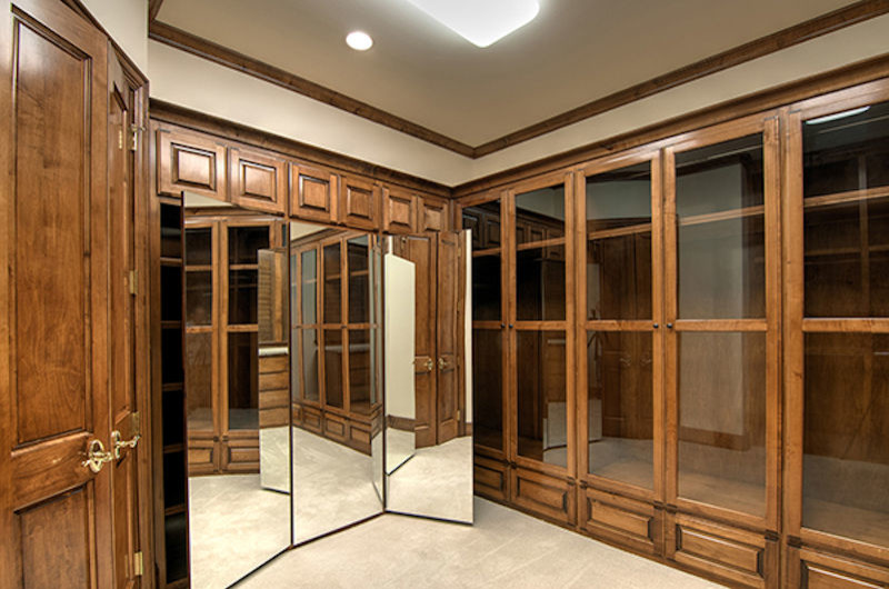 Photo of a large traditional men's walk-in wardrobe in Dallas with raised-panel cabinets, medium wood cabinets and carpet.
