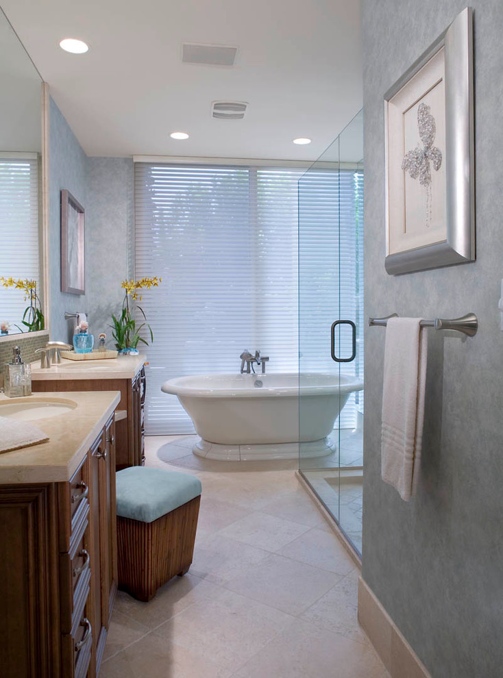 Photo of a traditional bathroom in Los Angeles with an undermount sink, recessed-panel cabinets, medium wood cabinets, marble benchtops, a freestanding tub, a curbless shower, beige tile and stone tile.