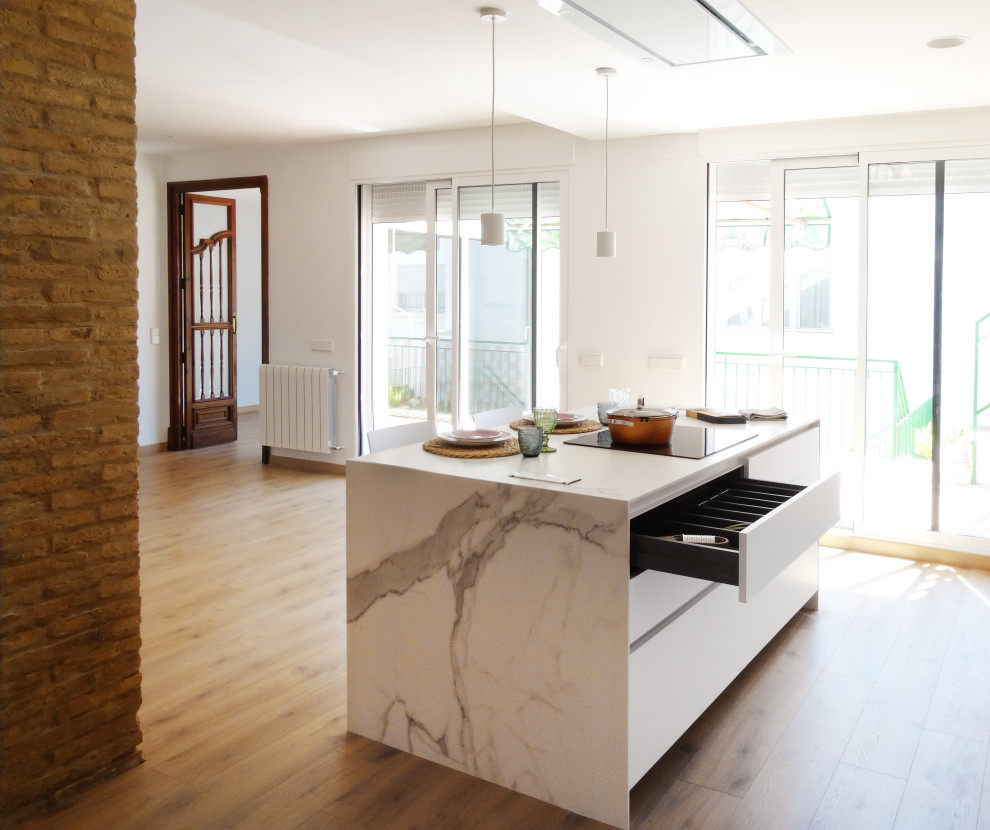 Inspiration för mellanstora moderna vitt kök med öppen planlösning, med en undermonterad diskho, släta luckor, vita skåp, vitt stänkskydd, rostfria vitvaror, mellanmörkt trägolv, en köksö och brunt golv