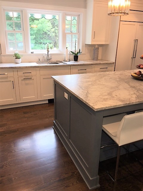Inspiration for a large transitional l-shaped eat-in kitchen in New York with an undermount sink, beaded inset cabinets, white cabinets, quartzite benchtops, white splashback, porcelain splashback, stainless steel appliances, dark hardwood floors, with island and brown floor.