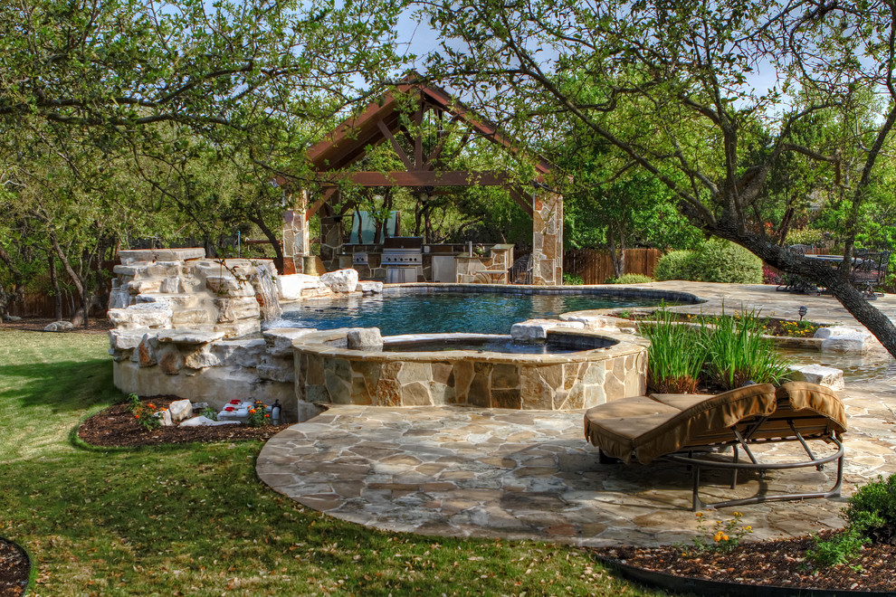 Mid-sized traditional backyard custom-shaped natural pool in Austin with natural stone pavers and a hot tub.