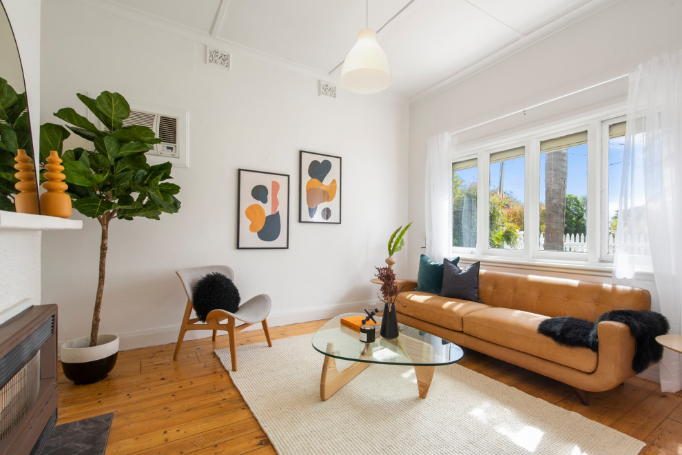 Immagine di un piccolo soggiorno minimalista chiuso con pareti bianche, pavimento in legno massello medio e camino classico