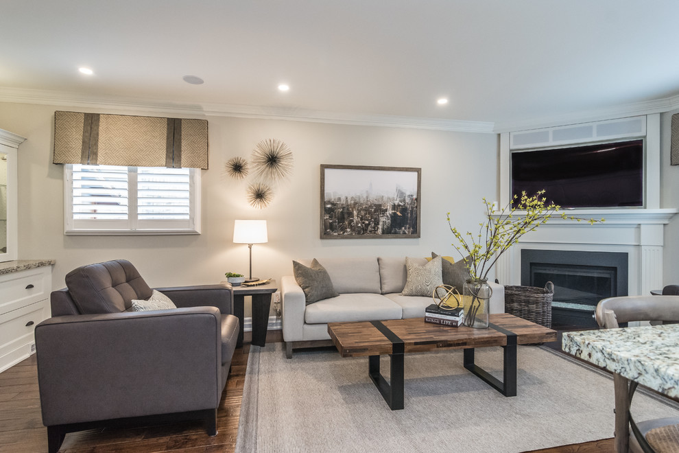 Mid-sized transitional open concept living room in Other with grey walls, medium hardwood floors, a corner fireplace, a wood fireplace surround, a wall-mounted tv and brown floor.