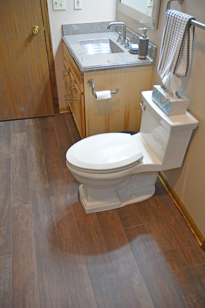 Inspiration for a mid-sized rustic master brown tile and ceramic tile ceramic tile and brown floor alcove shower remodel with raised-panel cabinets, light wood cabinets, a two-piece toilet, beige walls, an integrated sink, marble countertops, a hinged shower door and gray countertops