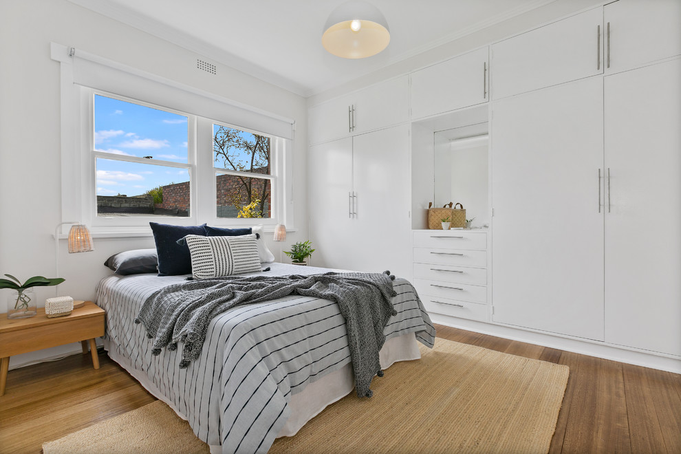 Photo of a contemporary master bedroom in Hobart with white walls, medium hardwood floors and brown floor.