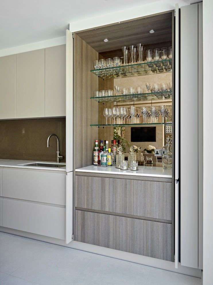 Photo of a contemporary single-wall wet bar in London with an undermount sink, flat-panel cabinets, grey cabinets, mirror splashback, grey floor and white benchtop.