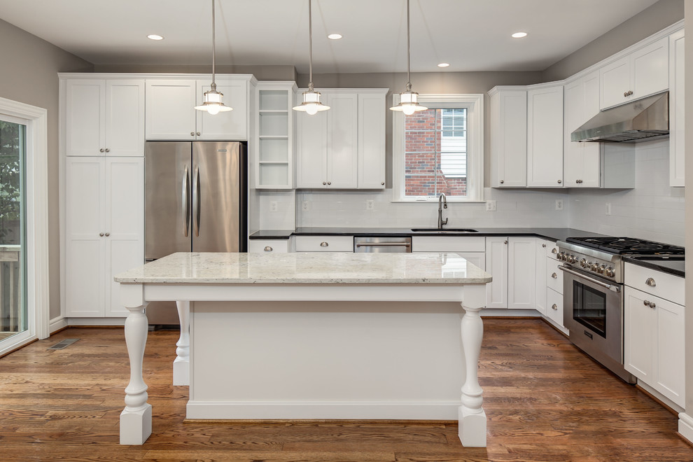 Design ideas for a large transitional l-shaped open plan kitchen in DC Metro with an undermount sink, shaker cabinets, white cabinets, white splashback, stainless steel appliances, medium hardwood floors, with island and subway tile splashback.