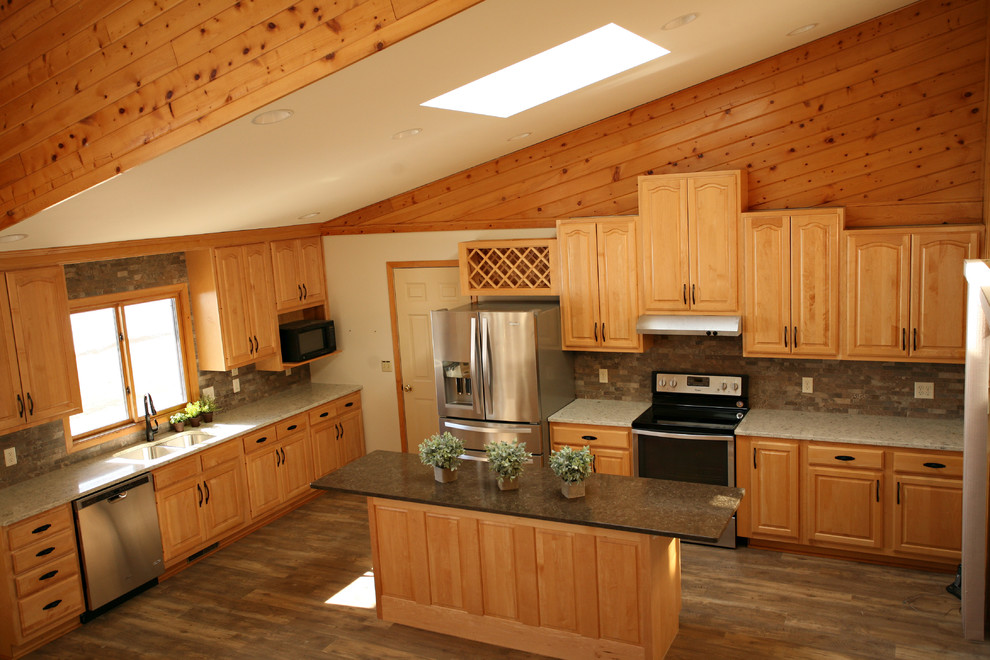 Mid-sized mountain style l-shaped medium tone wood floor and brown floor open concept kitchen photo with a double-bowl sink, raised-panel cabinets, light wood cabinets, quartz countertops, gray backsplash, stone tile backsplash, stainless steel appliances and an island