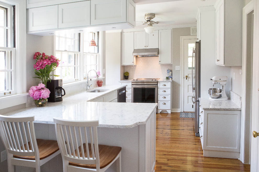 Kitchen - small transitional light wood floor kitchen idea with an undermount sink, shaker cabinets, white cabinets, quartz countertops, white backsplash, porcelain backsplash, stainless steel appliances and a peninsula