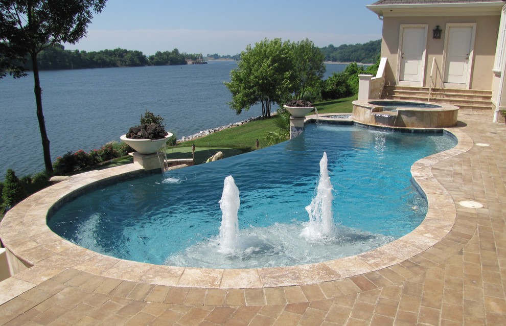 Photo of a mid-sized mediterranean backyard custom-shaped infinity pool in Atlanta with natural stone pavers and a hot tub.