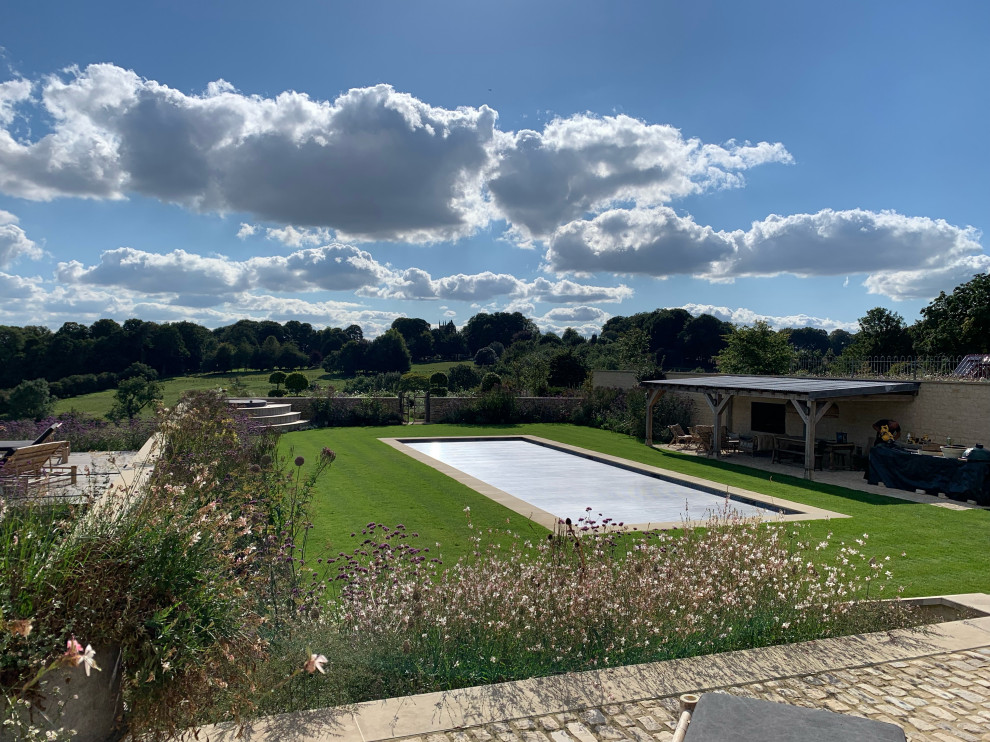 Inspiration for a medium sized country side rectangular above ground swimming pool in London with with pool landscaping and natural stone paving.