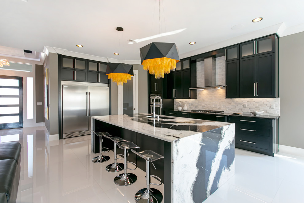 Inspiration for a transitional l-shaped kitchen in Seattle with an undermount sink, shaker cabinets, black cabinets, white splashback, stainless steel appliances, with island, white floor and black benchtop.