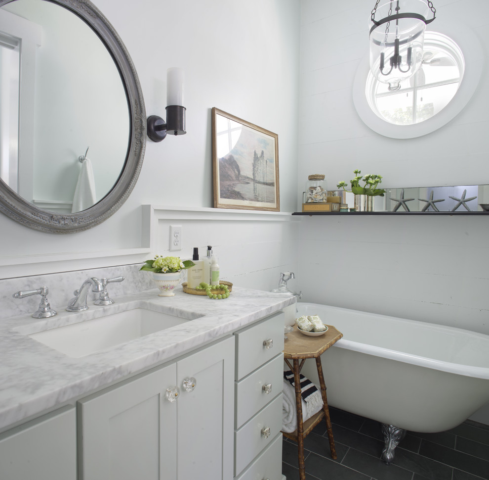 This is an example of a mid-sized beach style master bathroom in Atlanta with a claw-foot tub, marble benchtops, shaker cabinets, white cabinets, white walls, porcelain floors, an undermount sink, black floor and white benchtops.