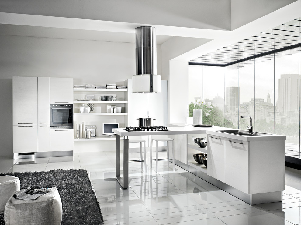 Inspiration for a mid-sized modern galley eat-in kitchen in San Diego with a double-bowl sink, flat-panel cabinets, white cabinets, solid surface benchtops, white splashback, ceramic splashback, panelled appliances, ceramic floors and a peninsula.