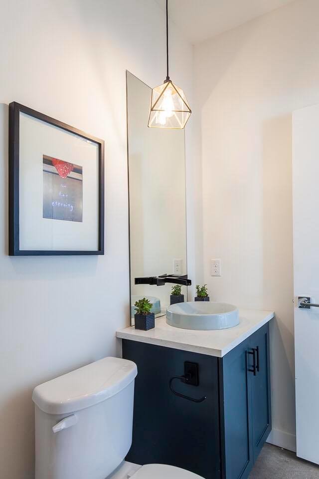 This is an example of a small contemporary powder room in Austin with shaker cabinets, blue cabinets, a two-piece toilet, white walls, concrete floors, a vessel sink and engineered quartz benchtops.