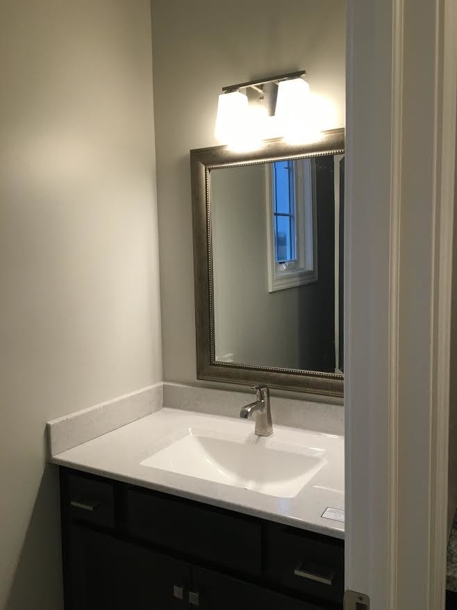 This is an example of a small traditional powder room in Chicago with recessed-panel cabinets, dark wood cabinets, beige walls, an integrated sink and solid surface benchtops.