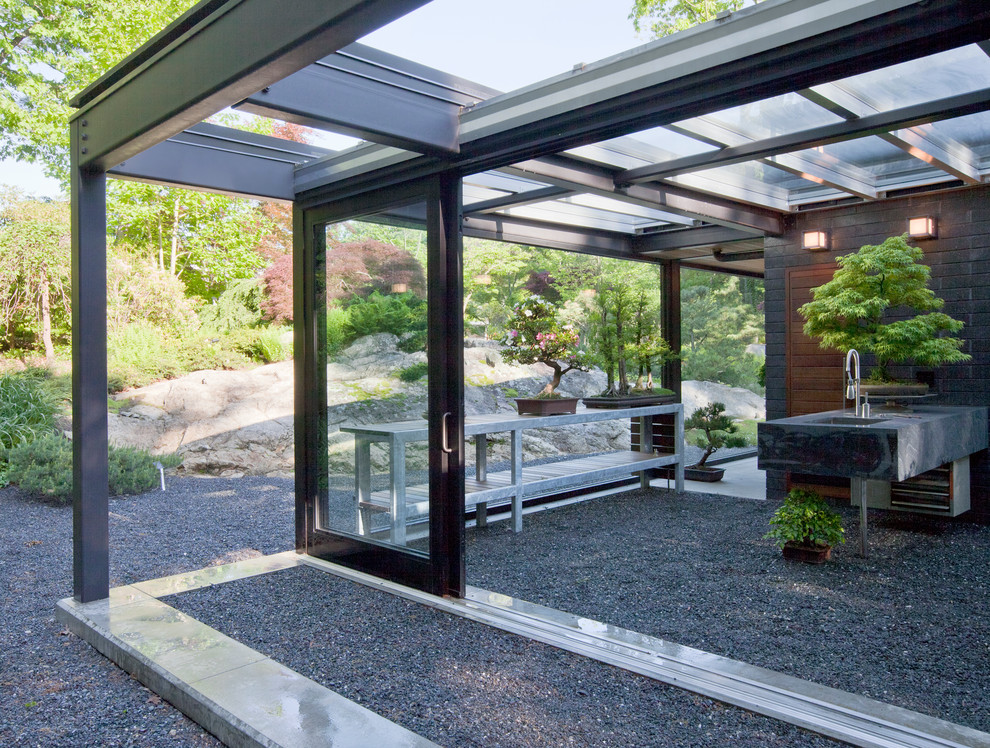 This is an example of a small modern backyard patio in Boston with concrete slab and a roof extension.
