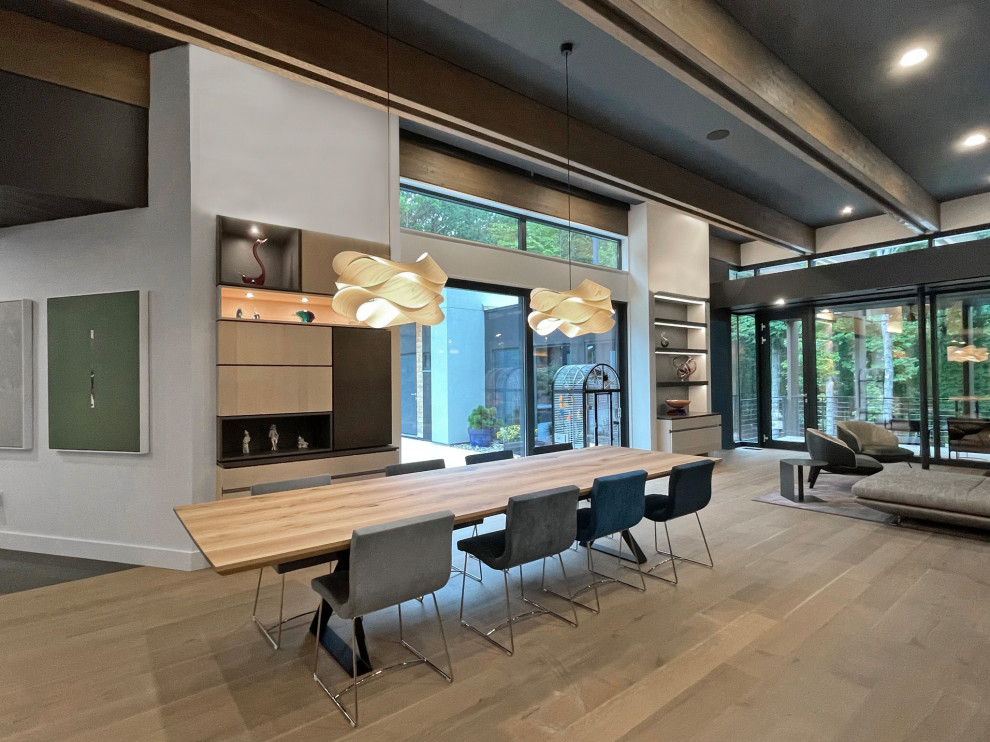 Foto de salón abierto minimalista grande sin chimenea con paredes grises, suelo de madera clara, televisor retractable y vigas vistas