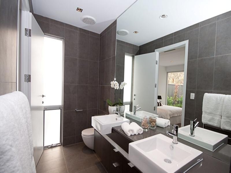 Photo of a mid-sized contemporary bathroom in Adelaide with solid surface benchtops, a wall-mount toilet and gray tile.