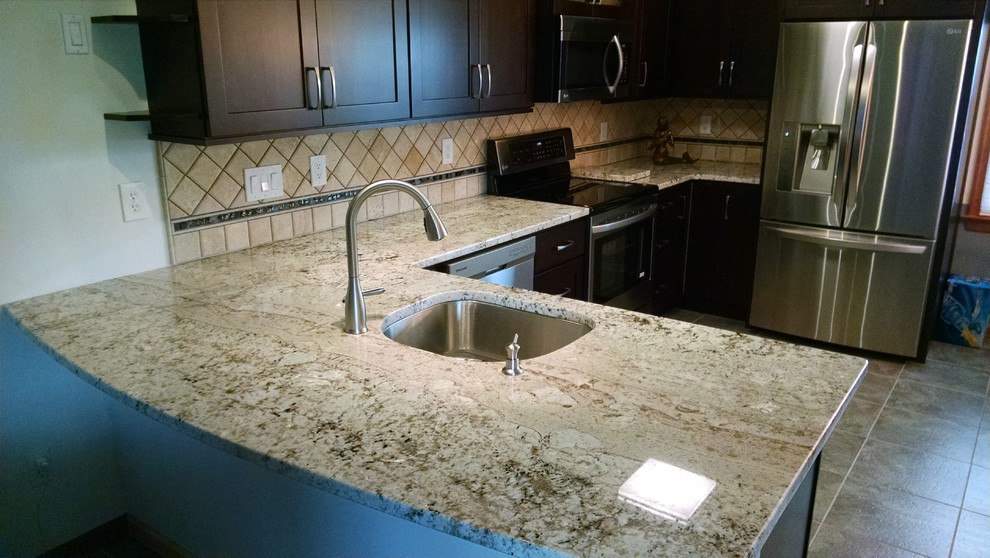 Mid-sized transitional u-shaped porcelain tile eat-in kitchen photo with an undermount sink, shaker cabinets, dark wood cabinets, granite countertops, beige backsplash, stone tile backsplash, stainless steel appliances and a peninsula