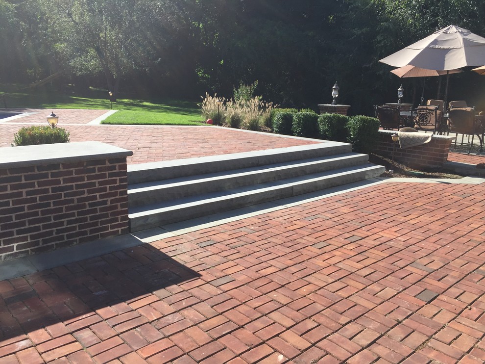 Design ideas for a large traditional backyard patio in New York with brick pavers.