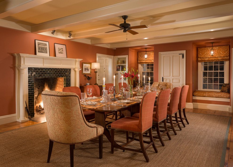Inspiration for a large country dining room in Burlington with light hardwood floors, a tile fireplace surround and orange walls.