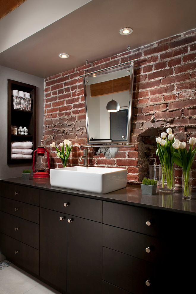 This is an example of an industrial bathroom in San Francisco with a vessel sink, flat-panel cabinets, dark wood cabinets and grey walls.
