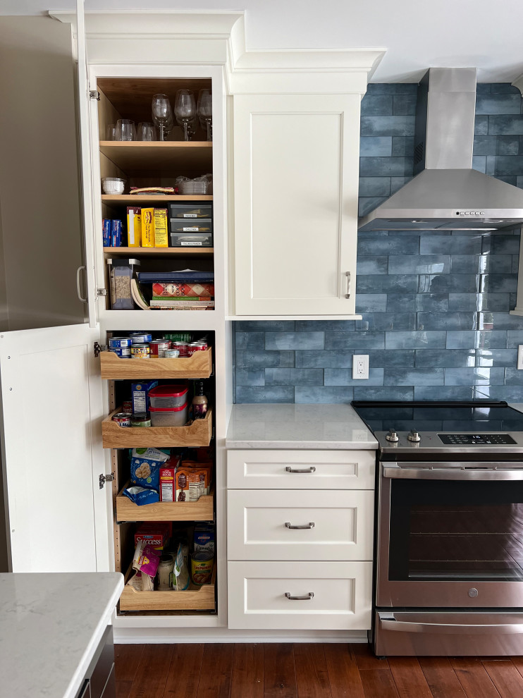 Mid-sized transitional u-shaped medium tone wood floor and brown floor eat-in kitchen photo in Cincinnati with an undermount sink, recessed-panel cabinets, white cabinets, quartz countertops, blue backsplash, glass tile backsplash, stainless steel appliances, an island and white countertops