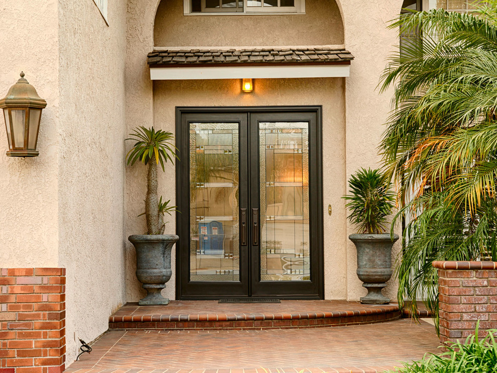 Photo of a large traditional front door in Orange County with beige walls, a double front door and a glass front door.